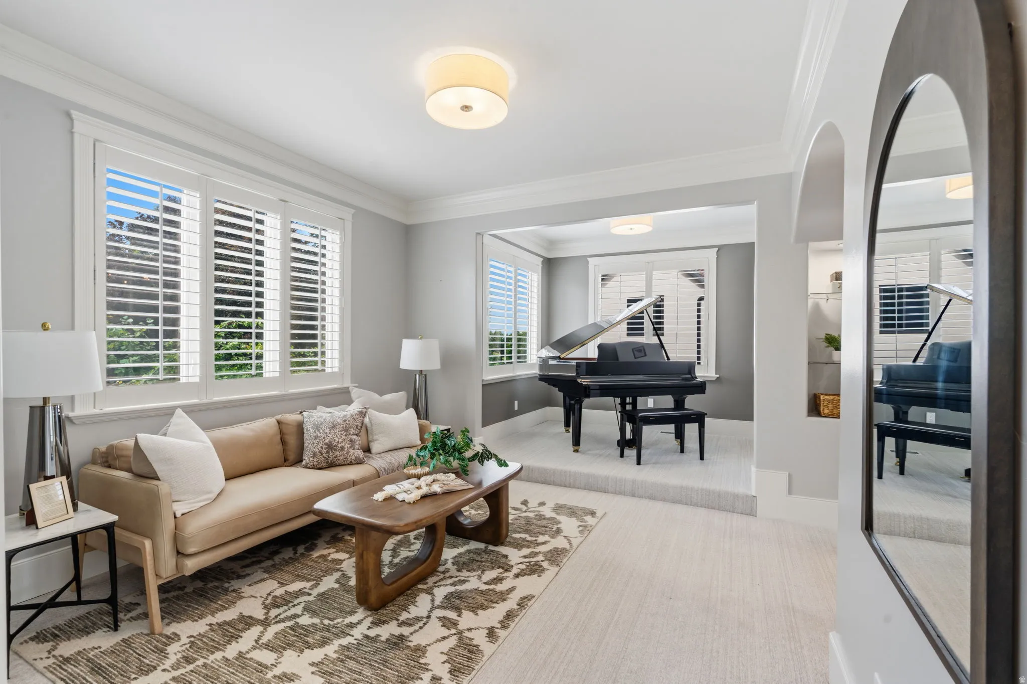 Recessed area with elevated platform, arched entryway, plantation shutters, and crown molding