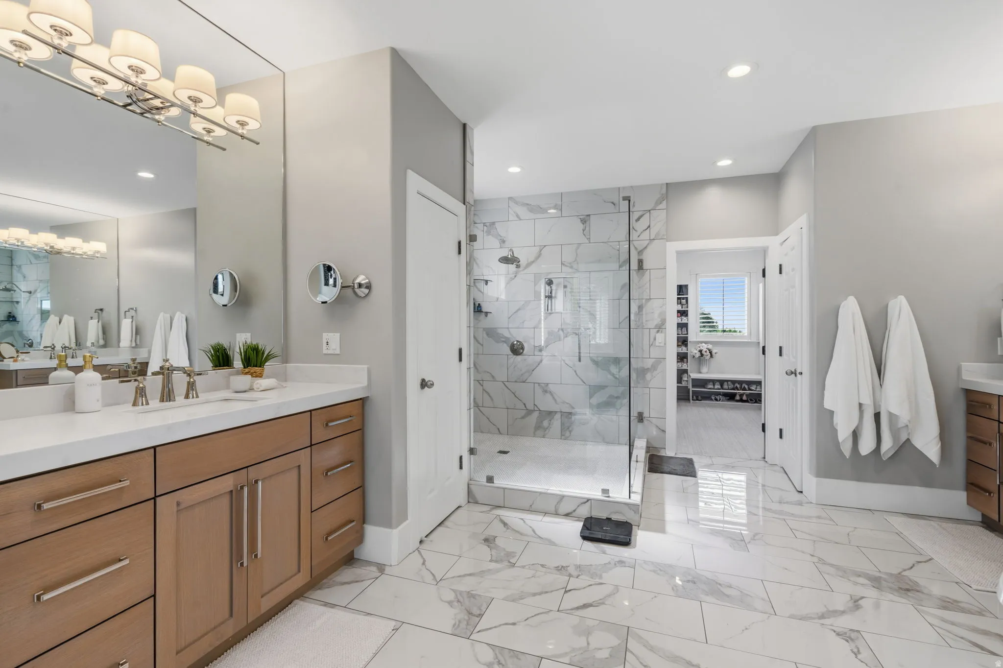 Oversized walk-in shower surrounded by clear glass features a sleek European-style swing door and an open, airy feel