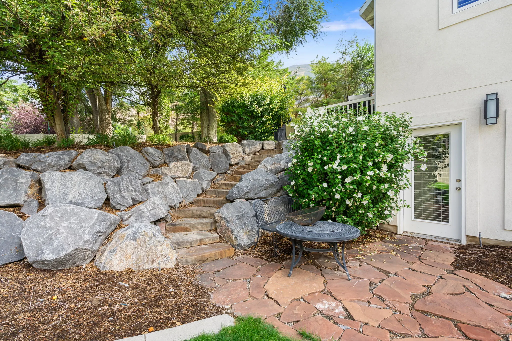 Side yard with integrated stone steps, flagstone patio, and access to Basement.  Possible ADU