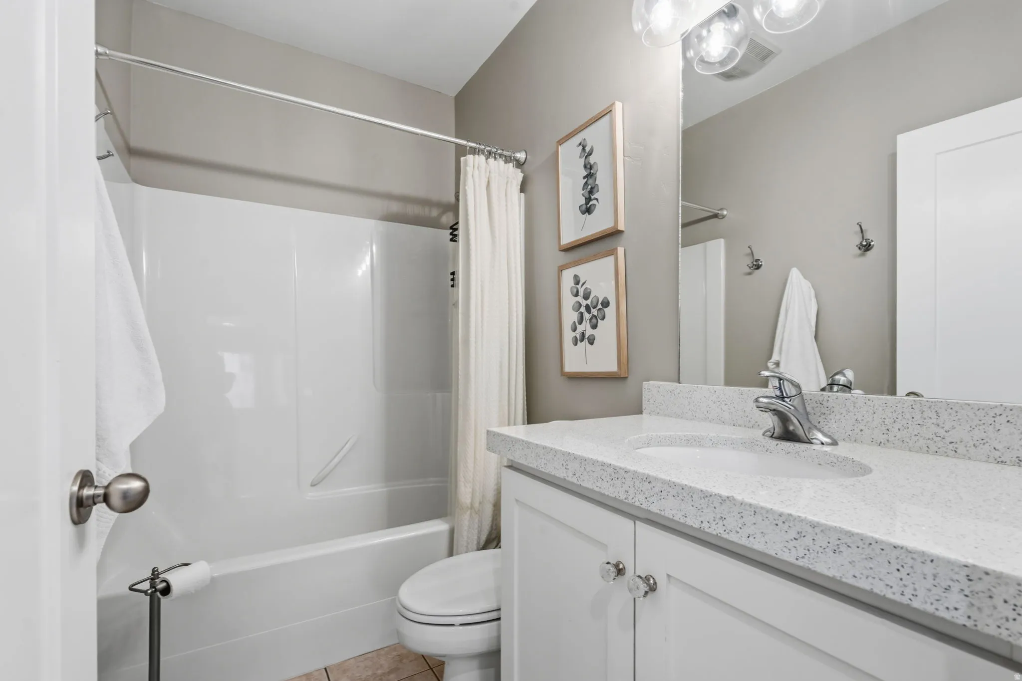 Convenient full bathroom with tub/shower combination, vanity with cabinet storage and toilet.
