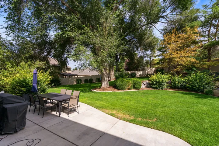 Expansive backyard featuring a lush lawn, mature trees, concrete patio, and landscaped perimeter with shrubbery.  RV Parking