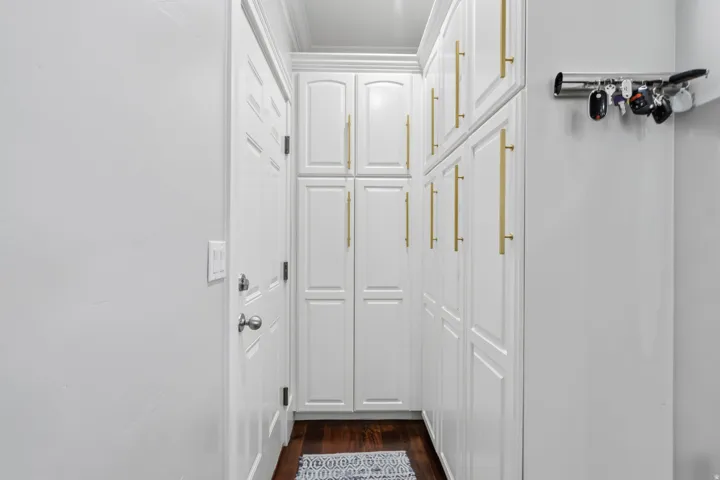 Floor-to-ceiling white cabinetry with gold-finish hardware