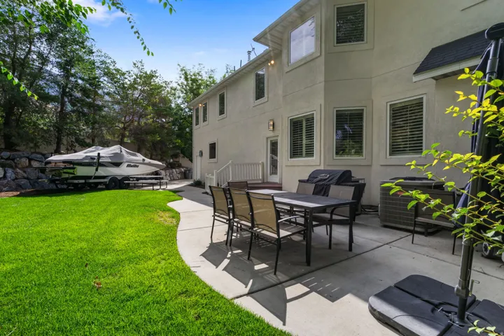Expansive backyard featuring a manicured lawn, concrete patio, and stone retaining wall. RV Pad as well!