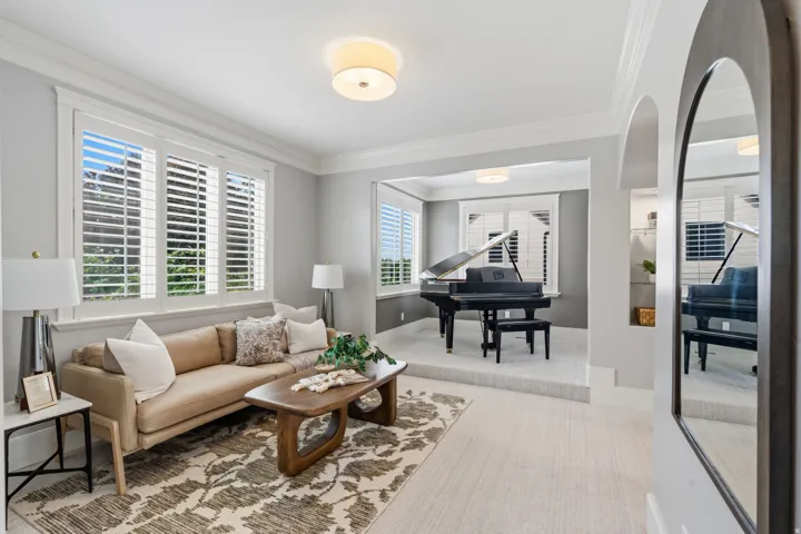Recessed area with elevated platform, arched entryway, plantation shutters, and crown molding