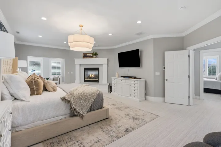 Expansive primary retreat entered thru double doors, featuring 9-foot ceilings, recessed lighting and a statement chandelier