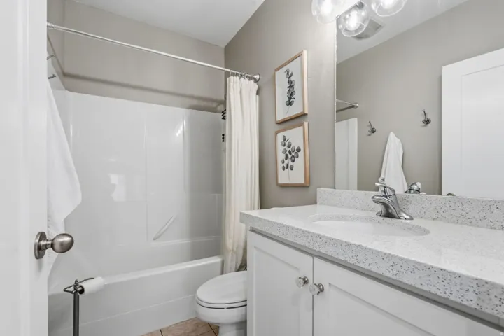 Convenient full bathroom with tub/shower combination, vanity with cabinet storage and toilet.