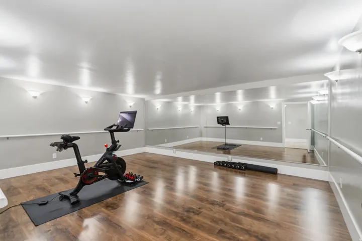 Large dedicated dance or fitness room with durable flooring and a full wall of floor-to-ceiling mirrors.