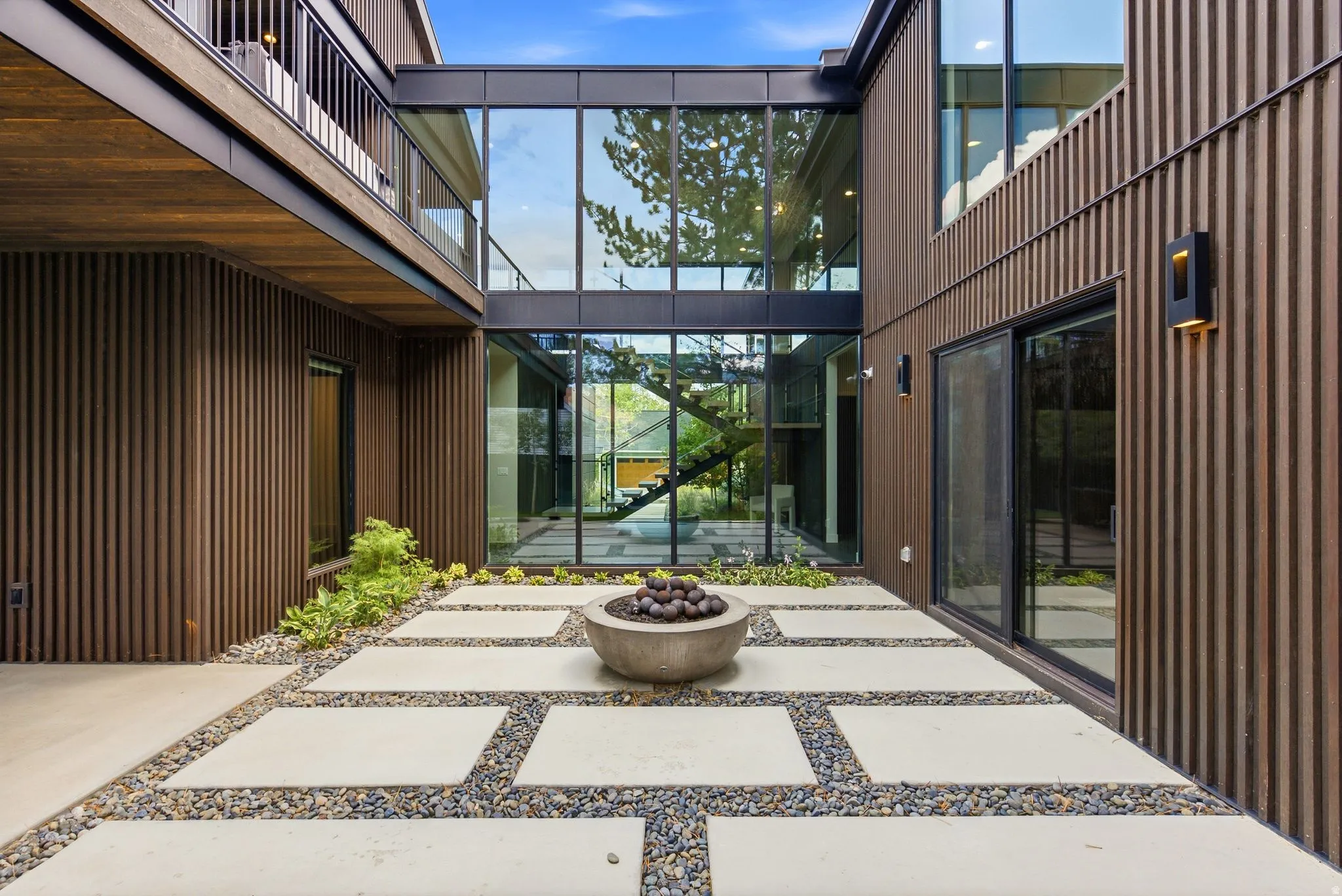 Contemporary courtyard featuring large format concrete pavers set in river rock, a built-in concrete fire pit, and integrated landscaping