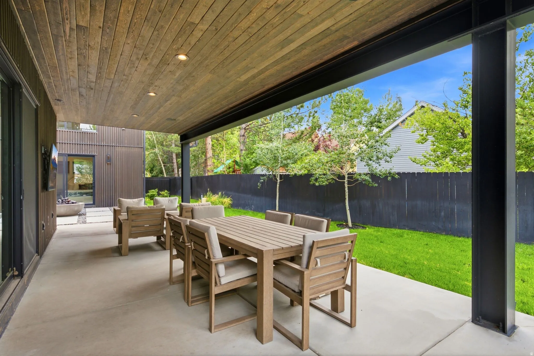 Covered patio featuring a wood-finish ceiling with recessed lighting, concrete flooring, and a corrugated metal exterior wall