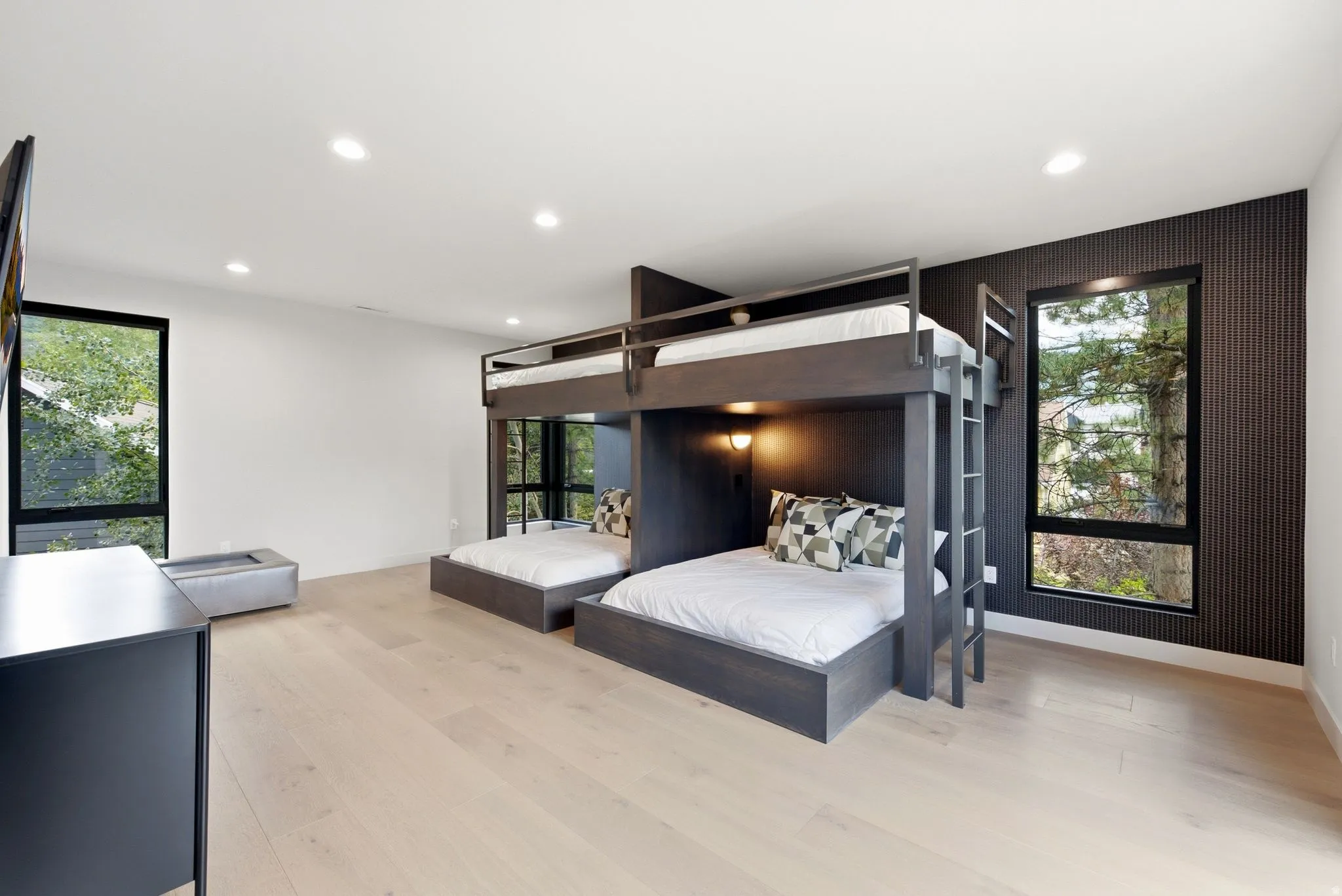 Spacious room featuring light wood-finish flooring, recessed lighting, and a prominent built-in bunk bed structure