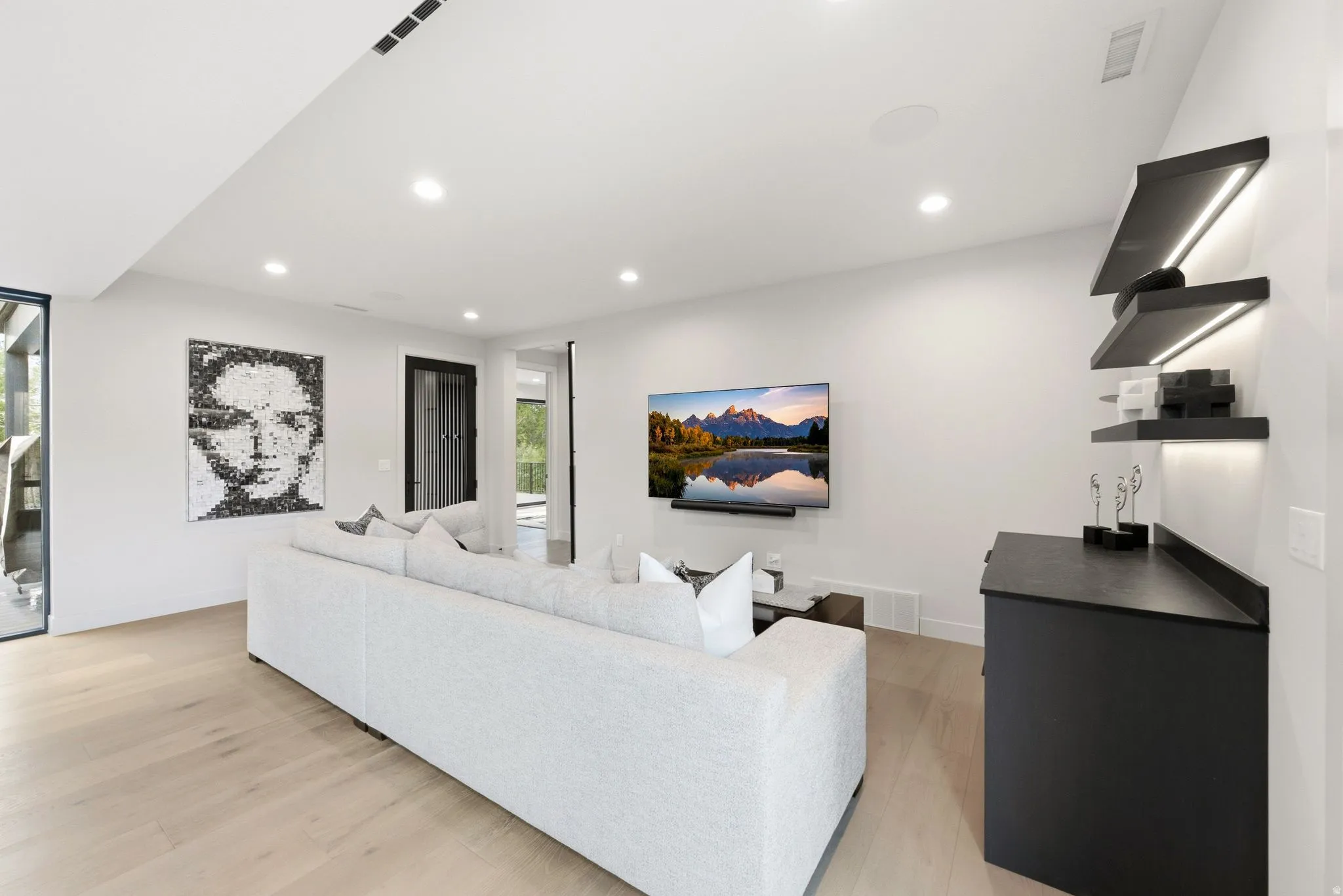 Open-concept living area featuring light wood-finish flooring, recessed lighting, and a mounted flat-screen television