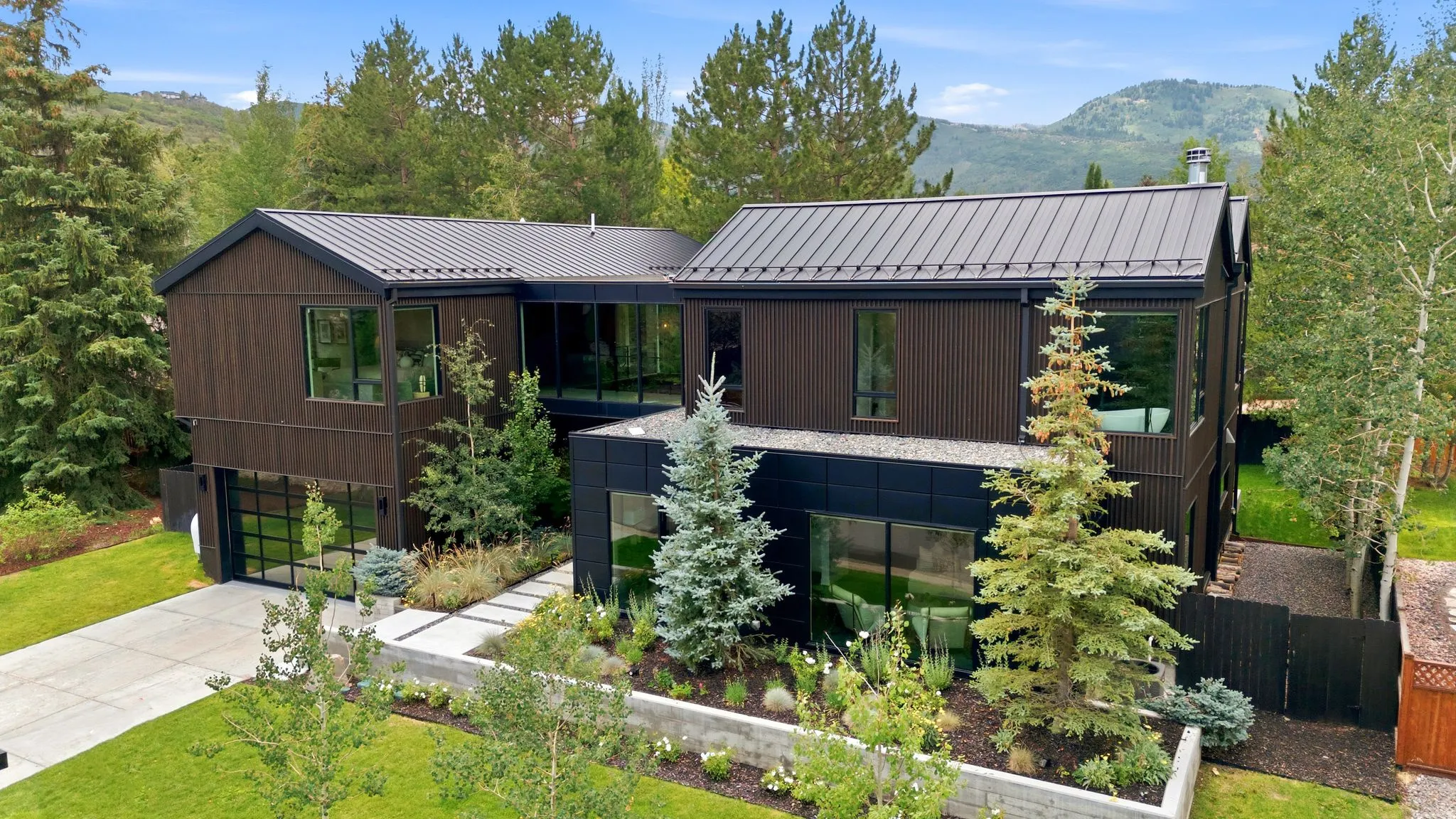 Contemporary architecture featuring dark wood siding, a standing seam metal roof, and extensive floor-to-ceiling windows