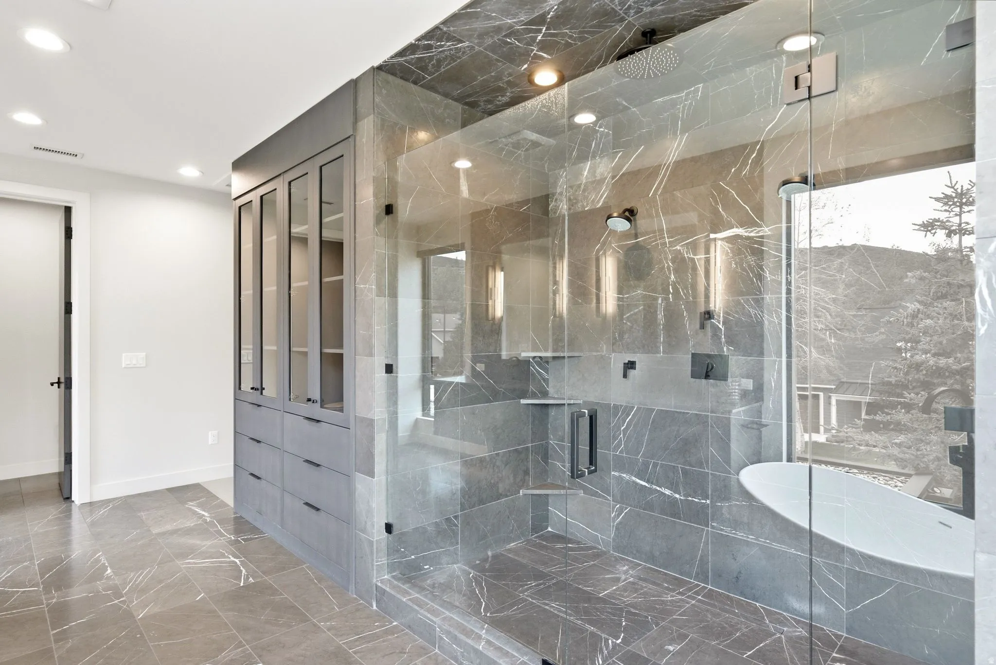 Frameless glass shower enclosure featuring multiple shower heads and a built-in bench