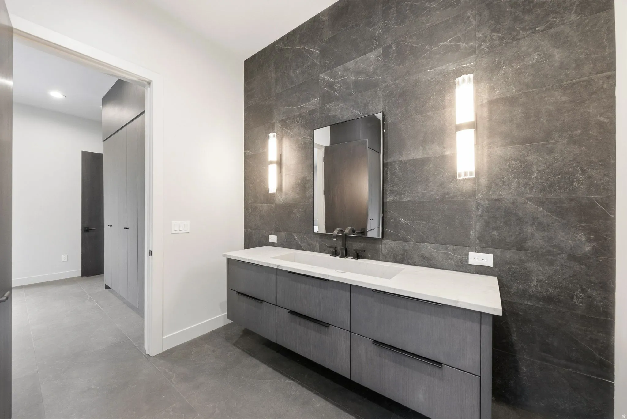 Floating vanity with a light countertop, integrated sink, and matte black faucet
