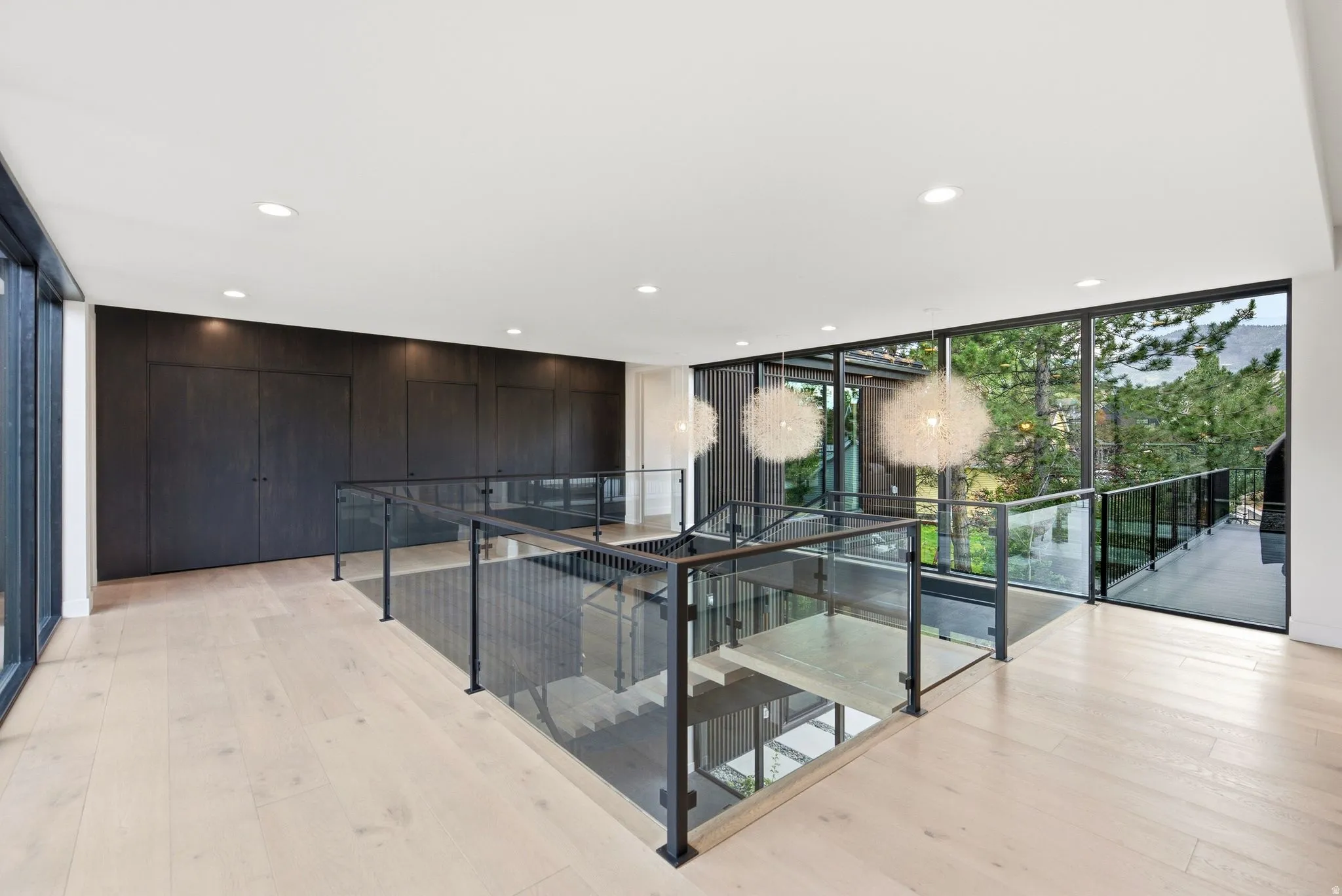 Upper-level landing featuring wide plank wood-finish flooring and a glass railing system