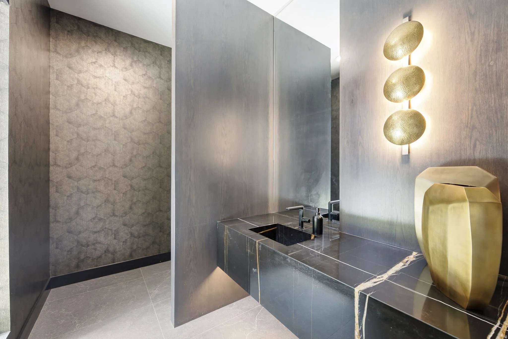 Modern vanity featuring a black stone countertop with white veining, an integrated sink, and matte black fixtures