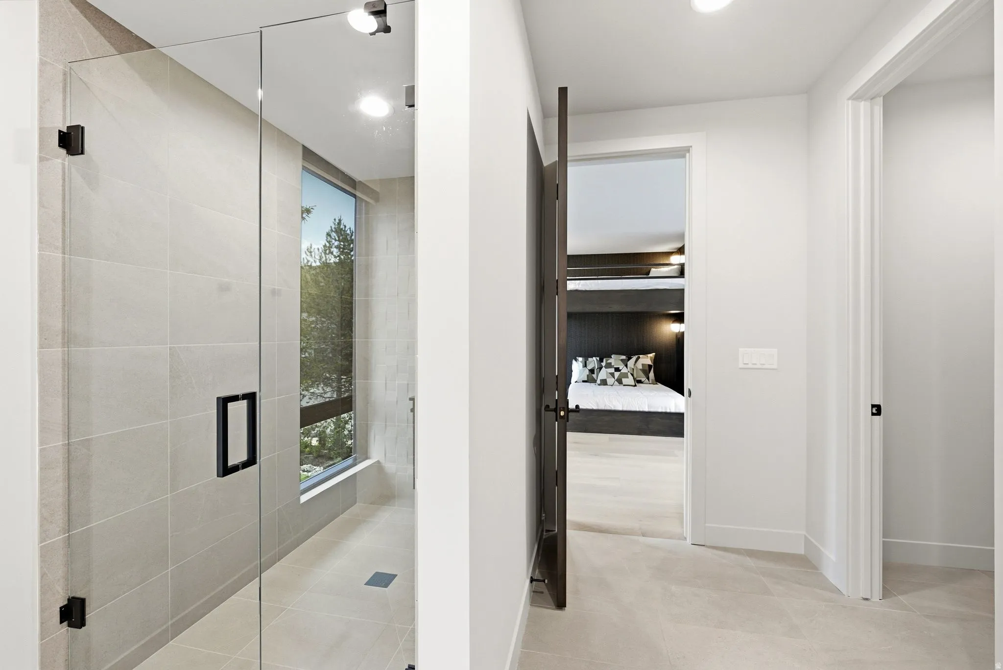 Glass-enclosed shower with large format tile, integrated lighting, and a large window