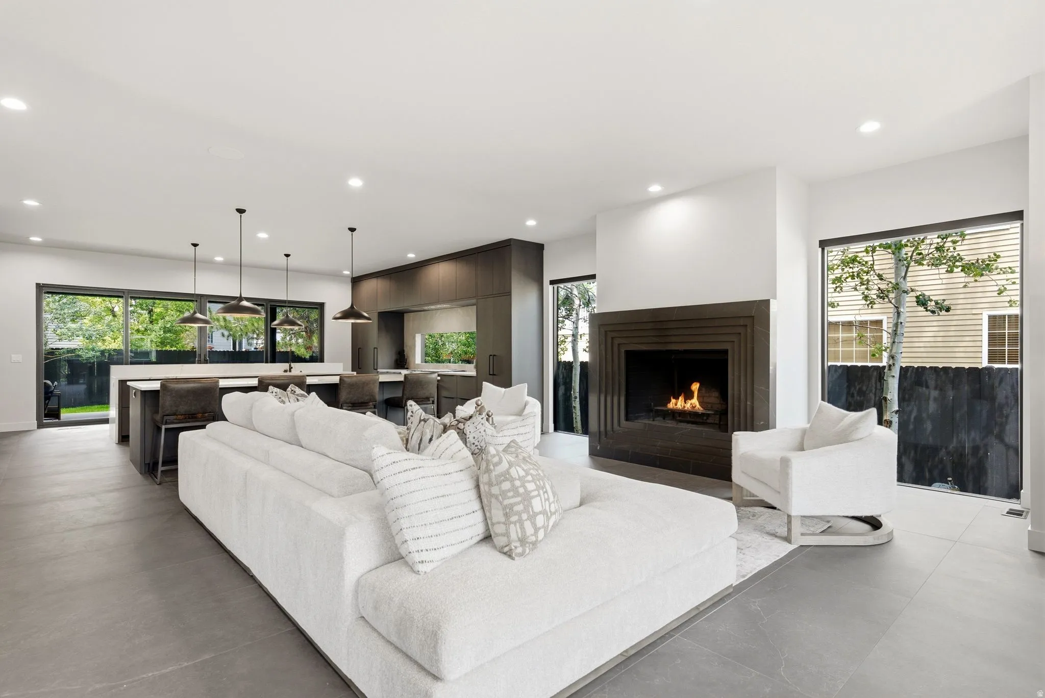 Open-concept living space featuring a modern fireplace with a dark stone surround, large format tile flooring, and recessed lighting
