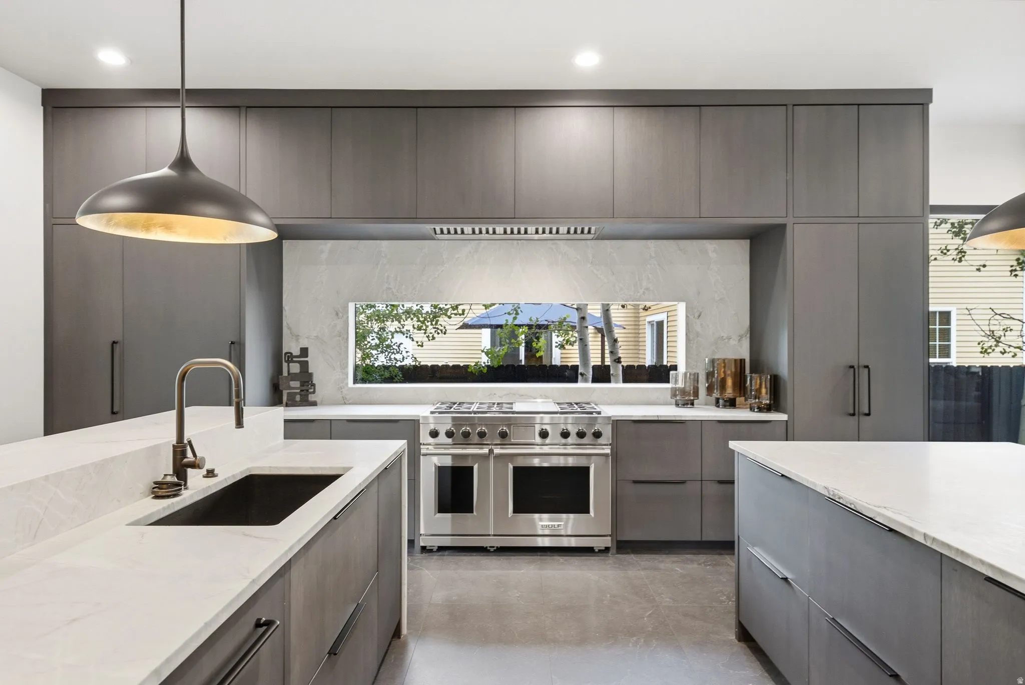 Sleek kitchen featuring full-height gray cabinetry, white countertops, and a stainless-steel range