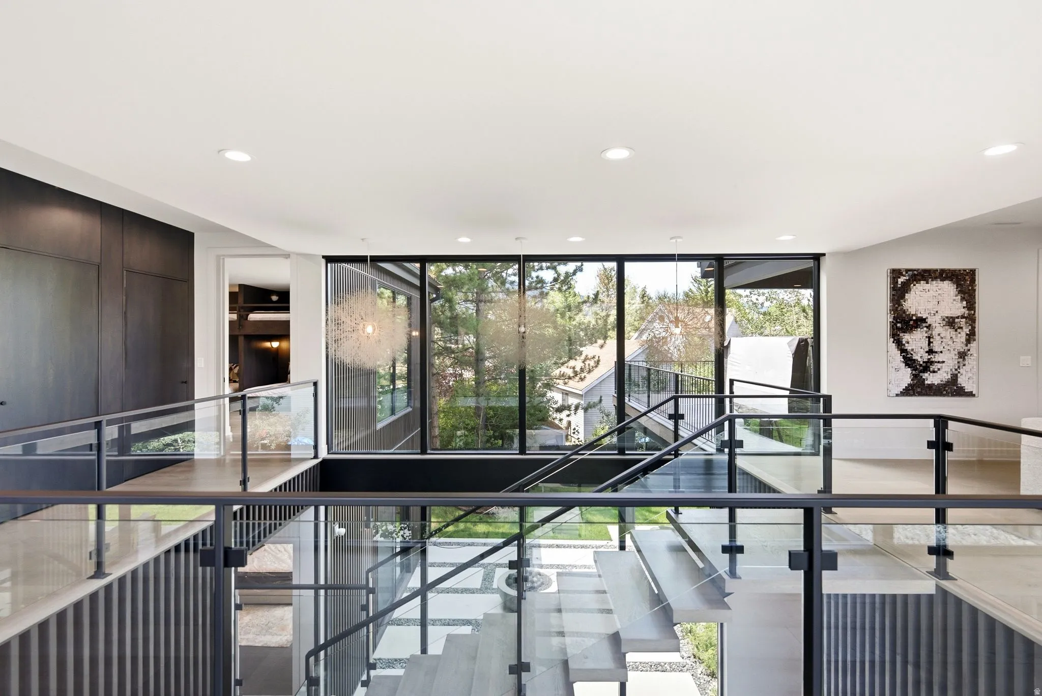 Multi-level interior featuring a contemporary staircase with glass railings and metal handrails