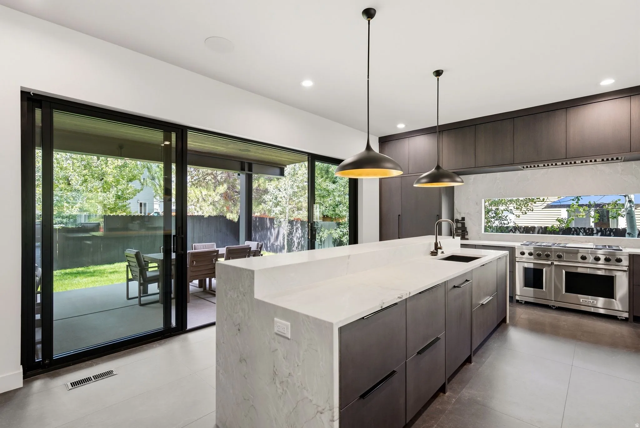 Modern kitchen featuring a large island with a waterfall countertop, integrated sink, and pendant lighting