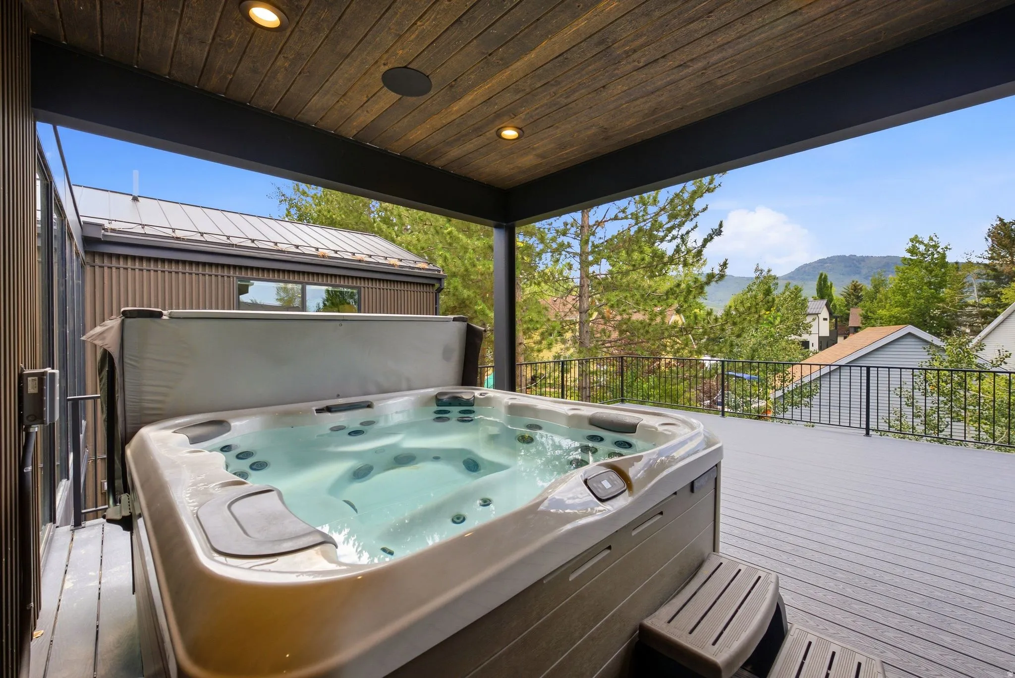 Expansive outdoor deck featuring a built-in hot tub, composite decking, and metal railings