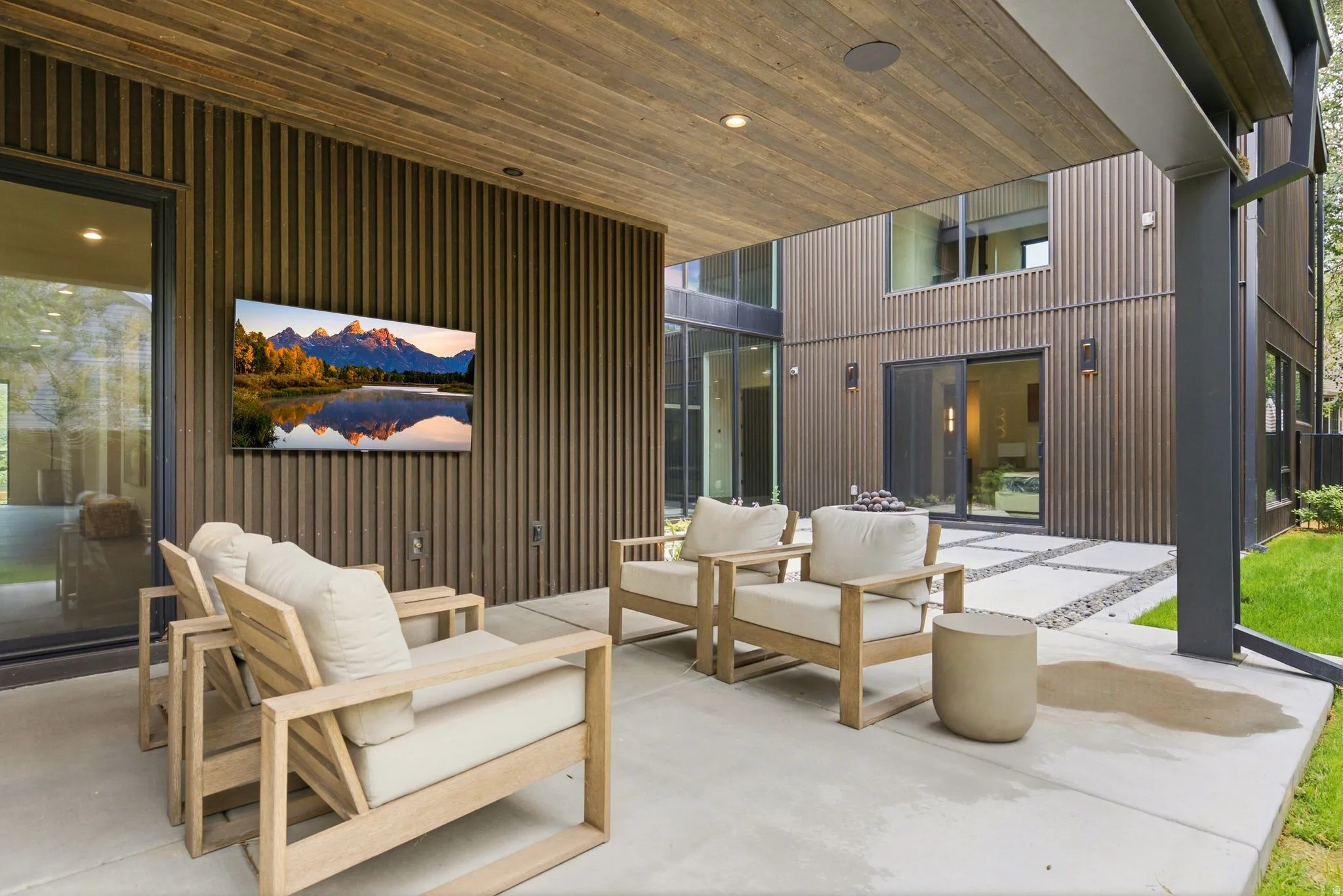 Covered patio featuring a wood-finish ceiling, mounted television, and contemporary vertical wood-panel siding