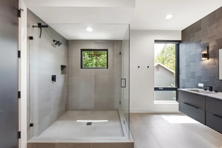 Contemporary bathroom featuring a spacious glass-enclosed shower with matte black fixtures, a built-in shower niche, and light gray tiled walls