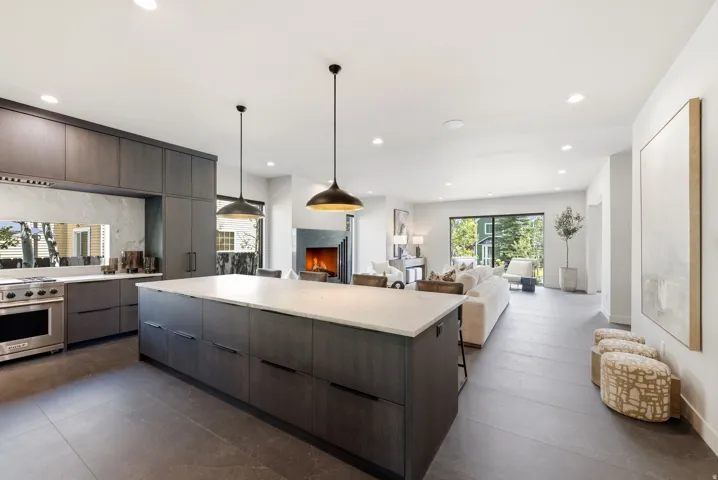 Contemporary kitchen featuring a large center island with a white countertop, dark wood-finish cabinetry, and stainless steel range