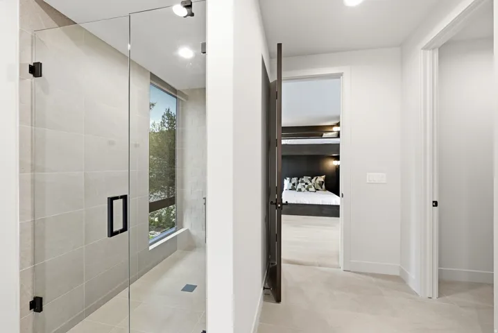 Glass-enclosed shower with large format tile, integrated lighting, and a large window