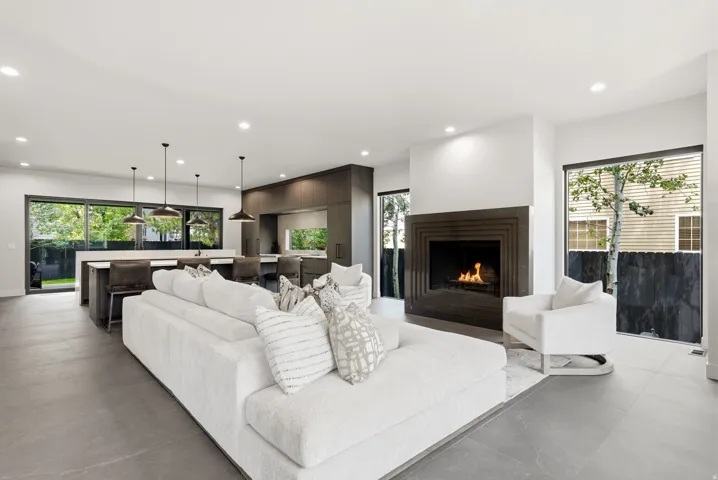Open-concept living space featuring a modern fireplace with a dark stone surround, large format tile flooring, and recessed lighting