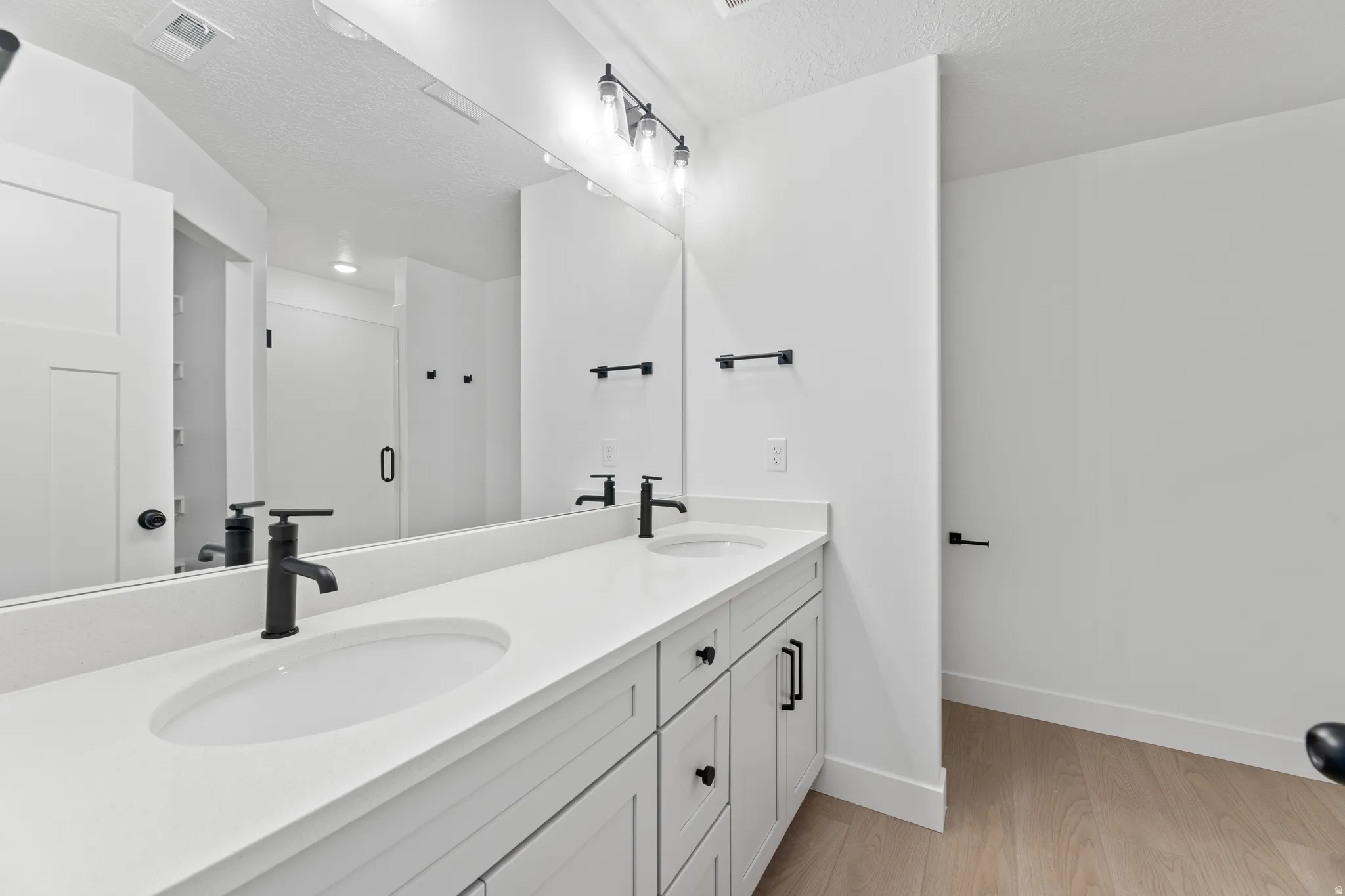 Dual vanity with solid surface countertop, undermount sinks, and matte black fixtures