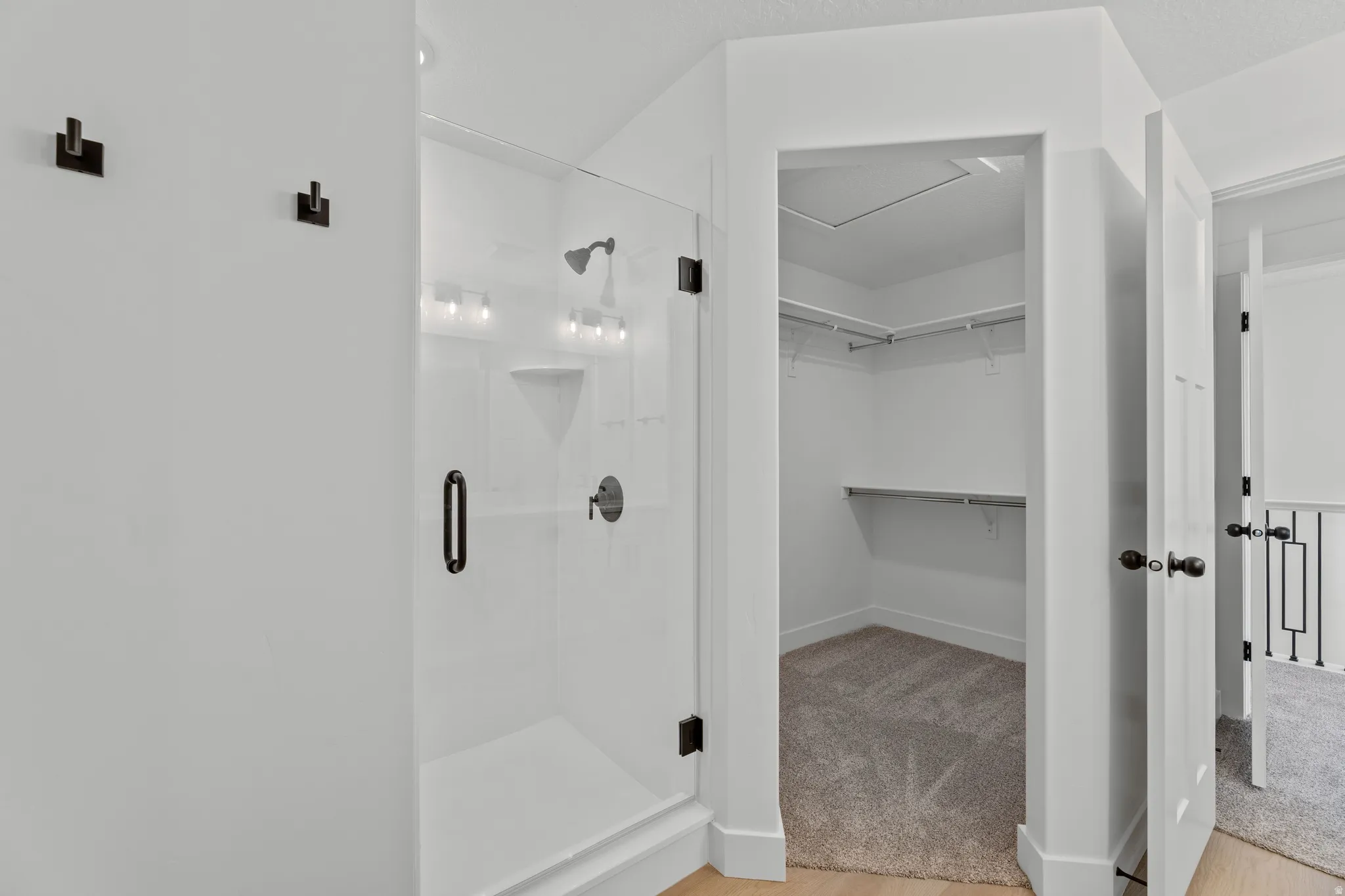 Modern glass-enclosed shower with matte black fixtures, integrated shelving, and a built-in shower bench