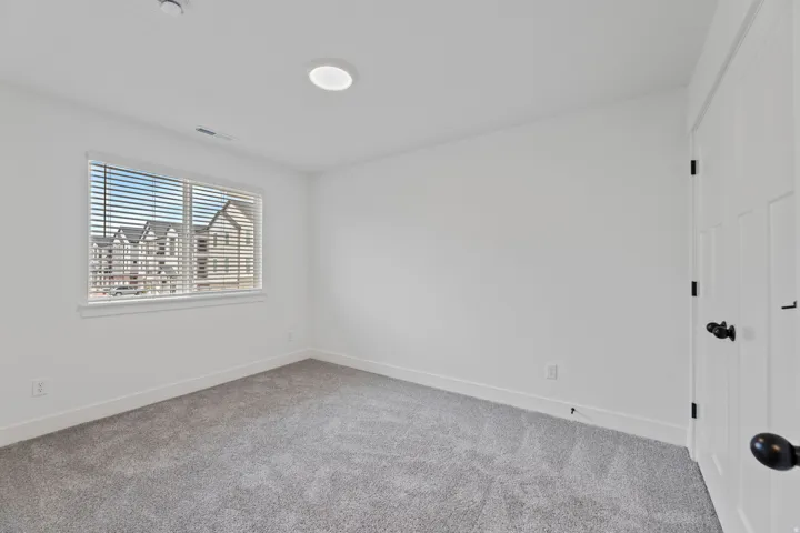 Room featuring light gray carpet flooring, white walls, and a window with white blinds