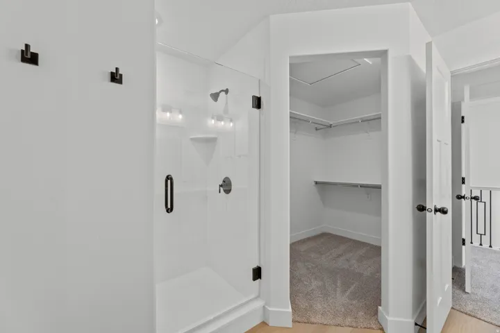 Modern glass-enclosed shower with matte black fixtures, integrated shelving, and a built-in shower bench