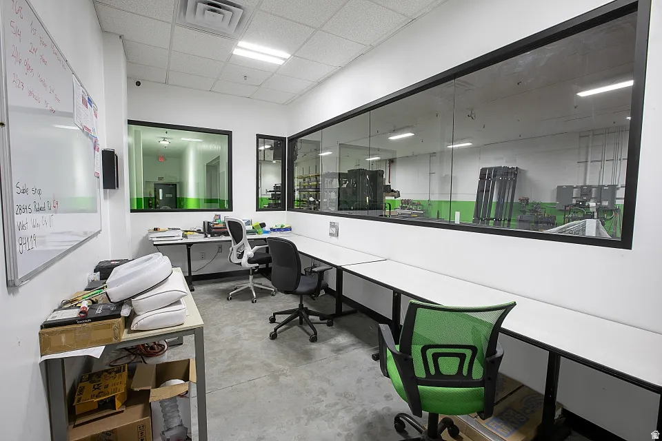 Open-plan office area featuring polished concrete flooring, white walls, and a dropped ceiling with recessed lighting