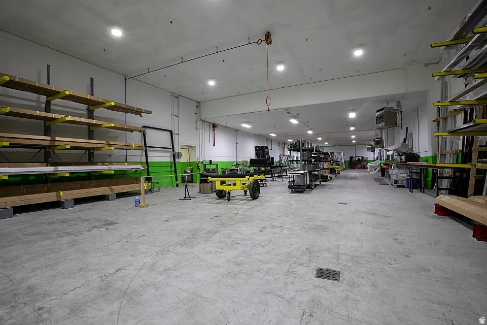Spacious warehouse interior featuring a concrete floor, high ceilings with recessed lighting, and wall-mounted shelving systems