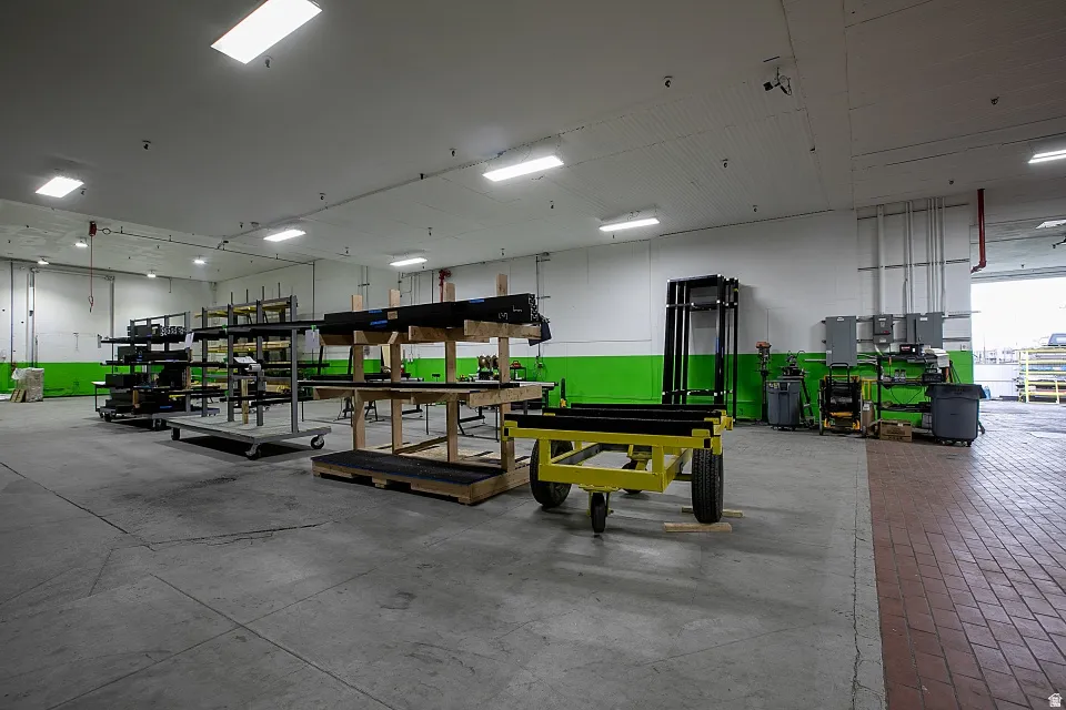 Spacious industrial interior featuring concrete flooring, a high ceiling with recessed lighting, and a roll-up door