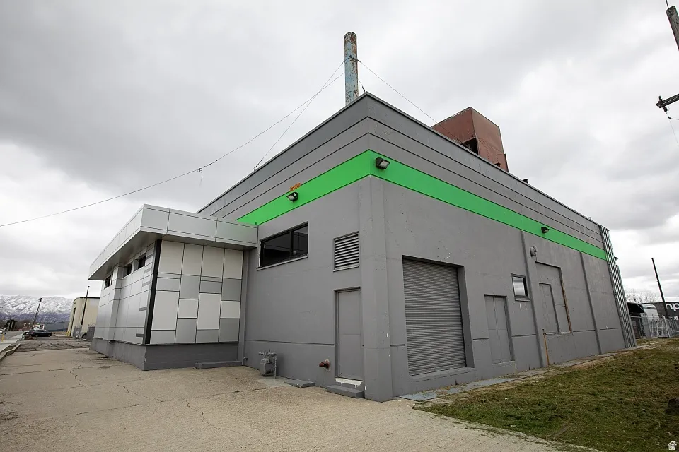 Industrial-style building featuring a gray exterior with a prominent green accent stripe