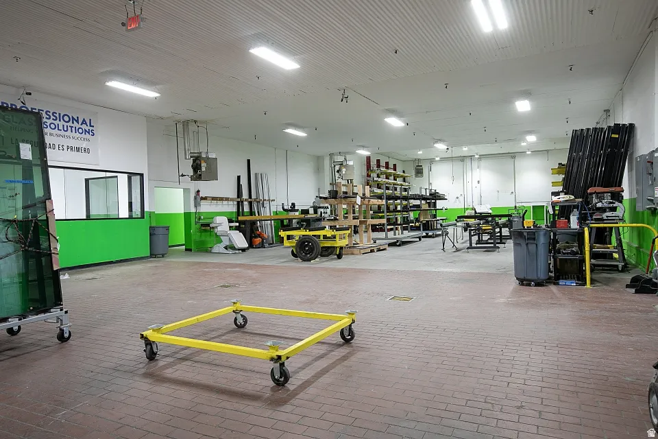 Spacious industrial interior featuring brick-patterned flooring, bright overhead fluorescent lighting, and a white corrugated ceiling