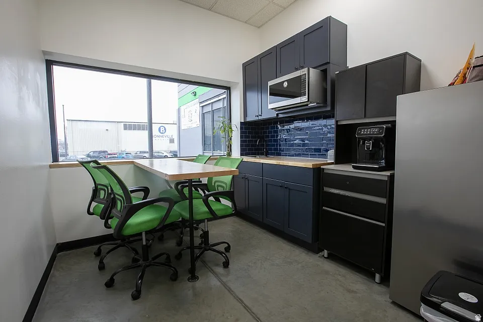 Modern kitchen area featuring dark blue cabinetry, wood-finish countertops, and a blue subway tile backsplash