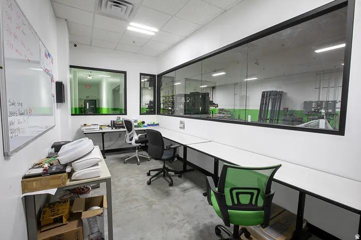 Open-plan office area featuring polished concrete flooring, white walls, and a dropped ceiling with recessed lighting