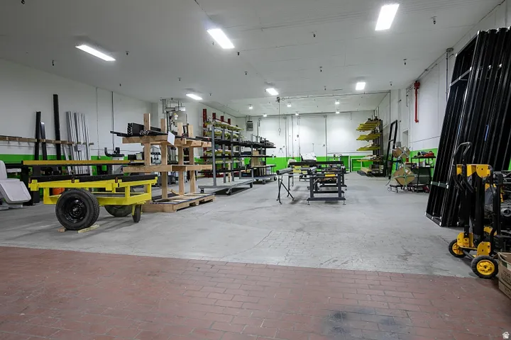 Spacious warehouse interior featuring a high ceiling with multiple fluorescent light fixtures
