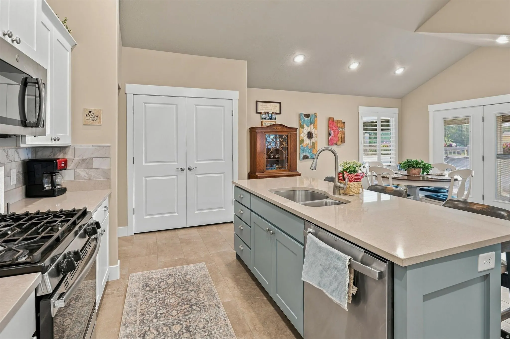 Kitchen featuring a central island with a double basin sink, light-toned countertops, and a full suite of stainless steel appliances