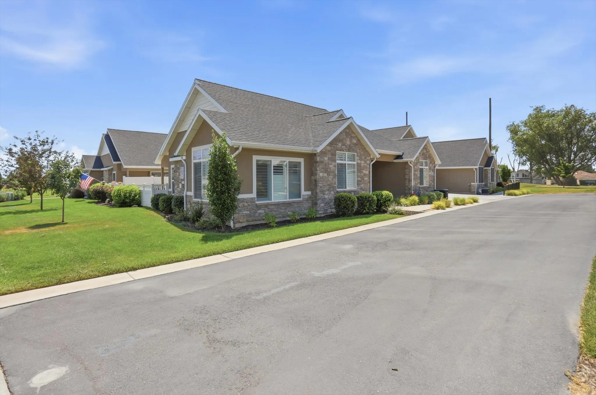 Exterior featuring stone and stucco finishes, multiple gables, white trim, and a shingle roof