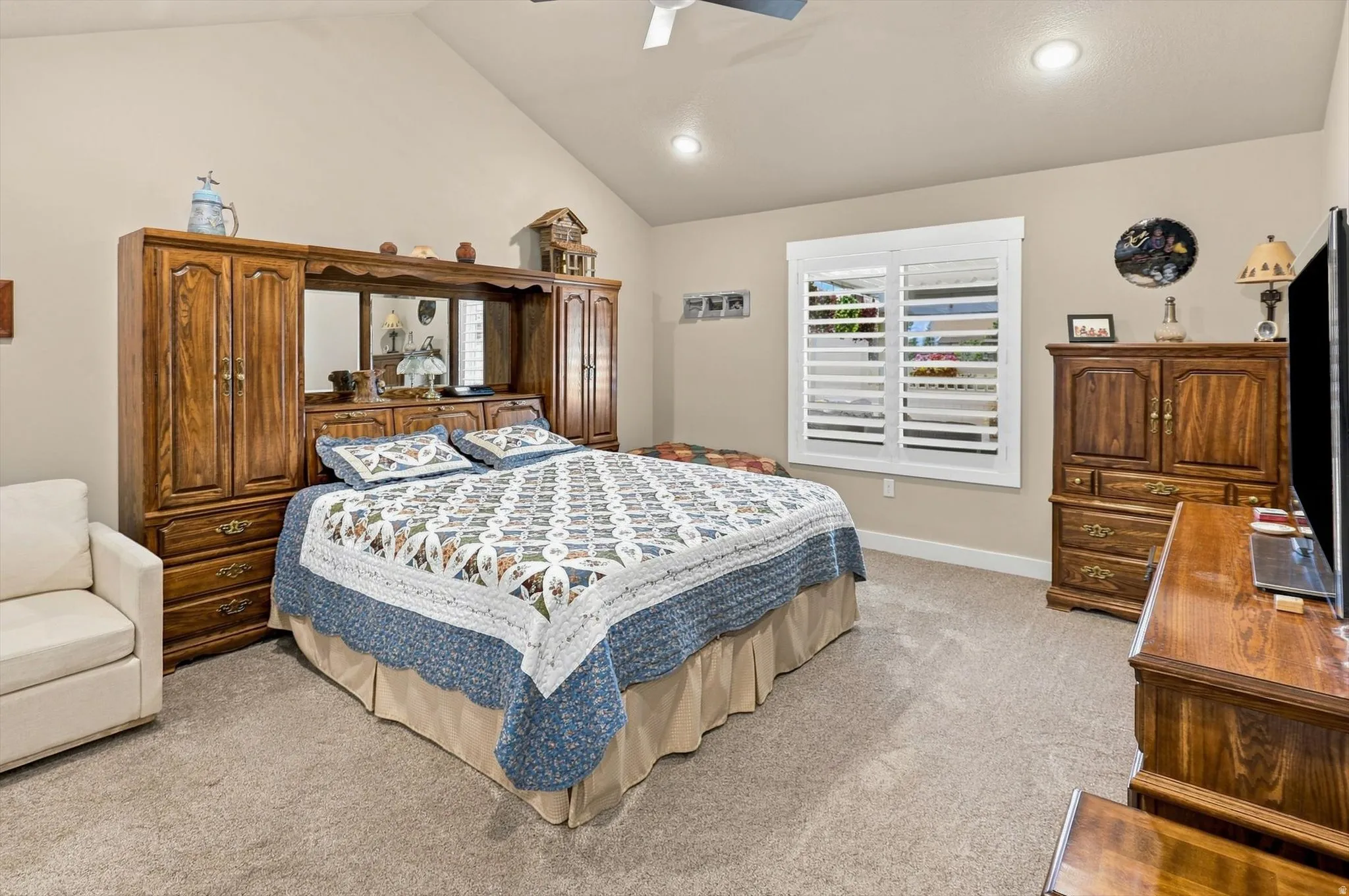 Vaulted ceiling bedroom with neutral wall tones and a ceiling fan