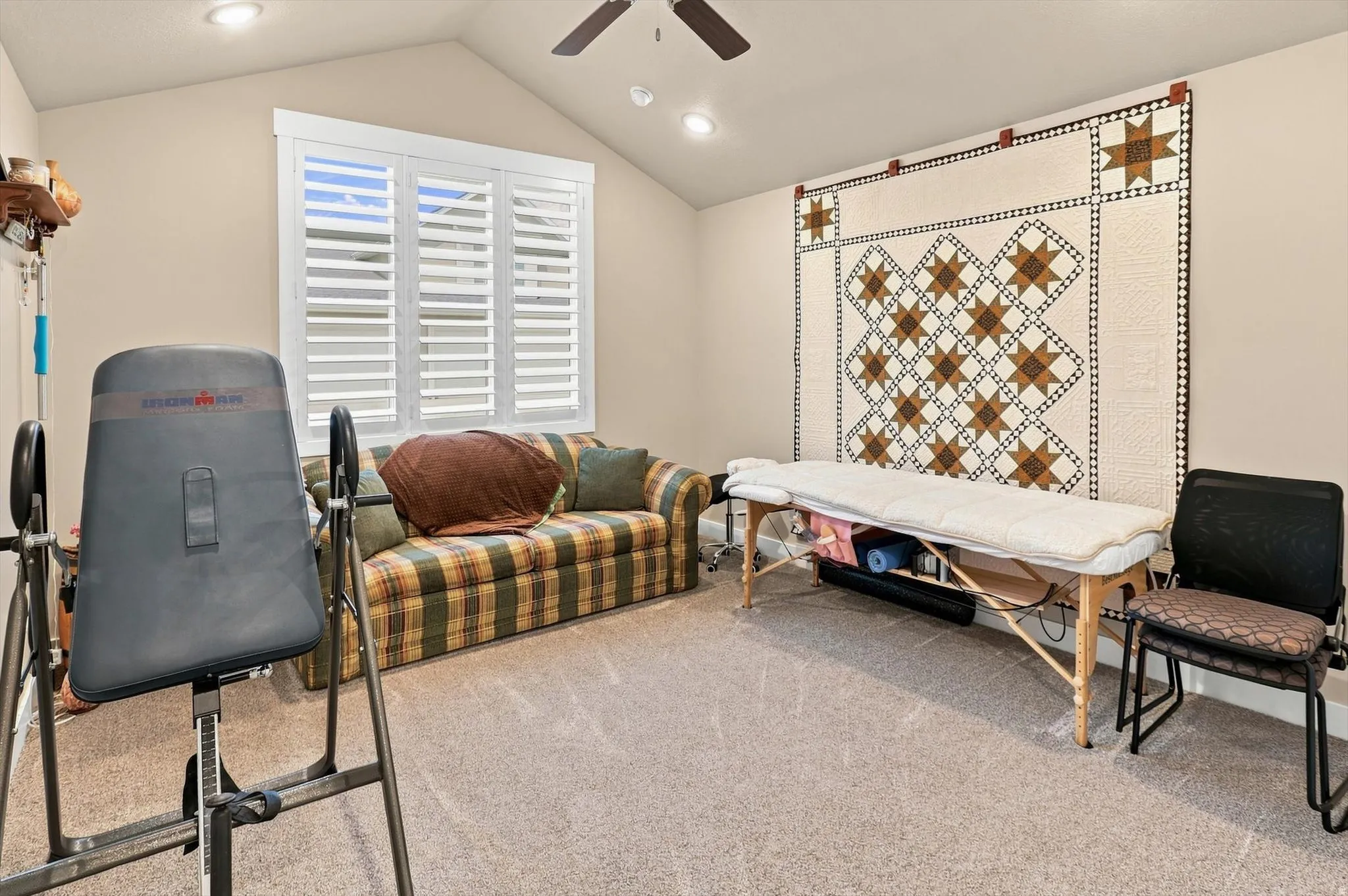 Vaulted ceiling with recessed lighting and a ceiling fan, featuring a window with plantation shutters and neutral carpet flooring