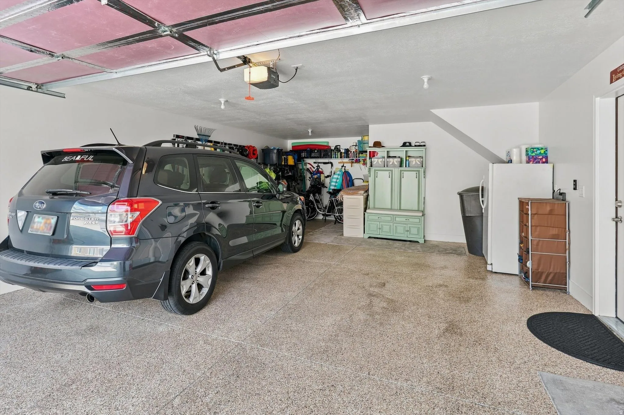 Spacious garage featuring a durable speckled epoxy floor, white painted walls, and an automatic garage door opener