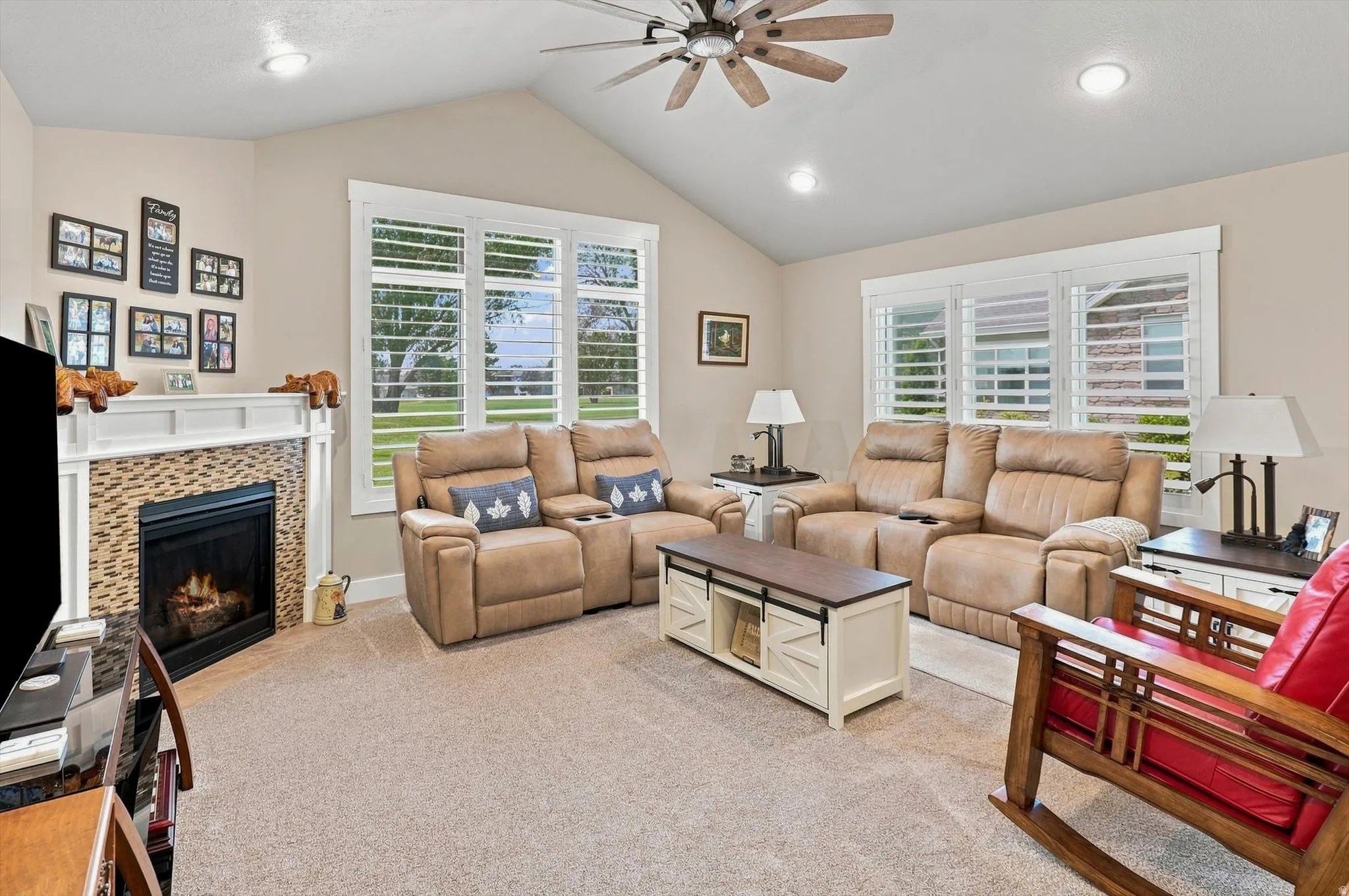 Vaulted ceiling living area featuring a fireplace with mosaic tile surround and white mantel, recessed lighting, and a ceiling fan