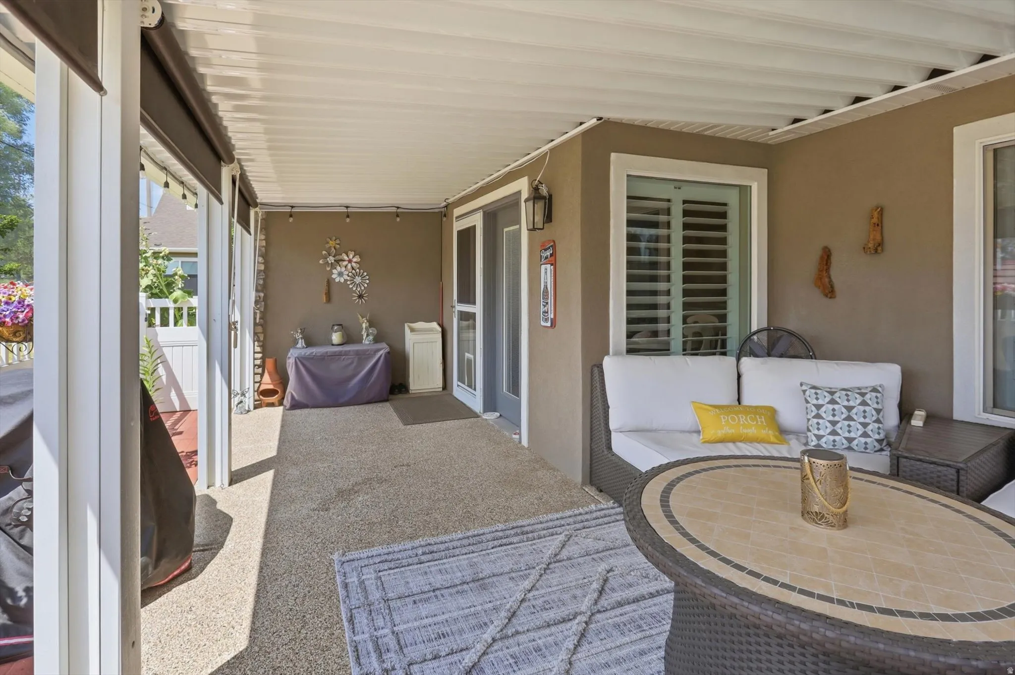 Covered patio featuring a textured floor, white ceiling, and exterior wall sconce